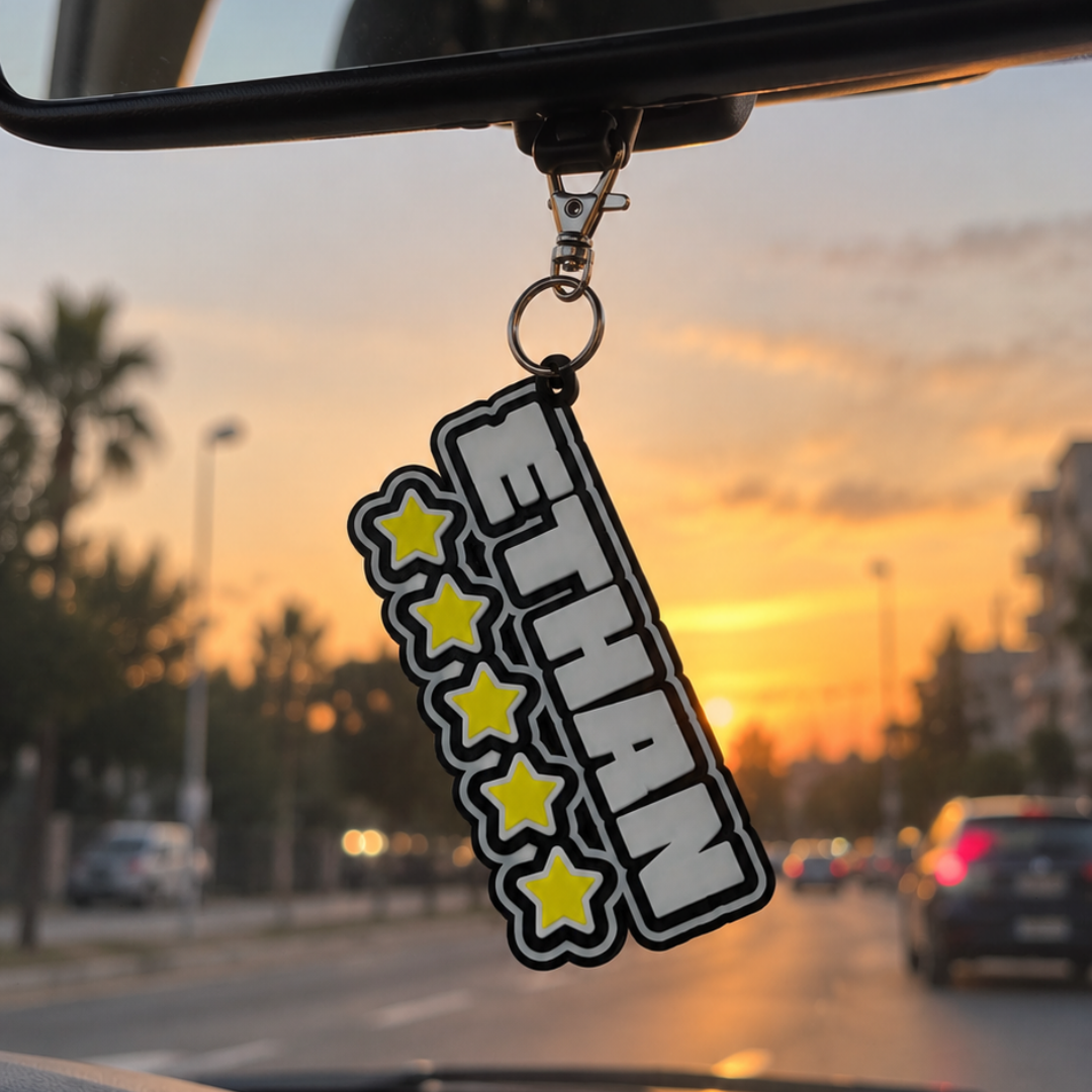 Llavero personalizable Beetle Print con nombre y cinco estrellas colgado del retrovisor interior de un coche