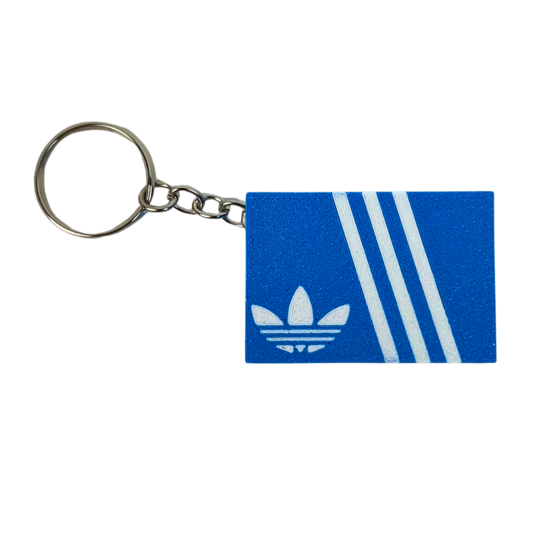 Llavero clicker Beetle Print Retro Stripes mostrado de frente con caja azul, líneas blancas y anilla metálica