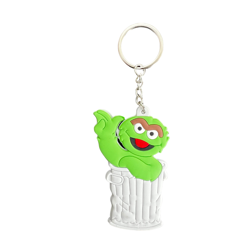 Llavero de silicona personaje verde estilo cartoon asomando desde cubo metálico con anilla plateada