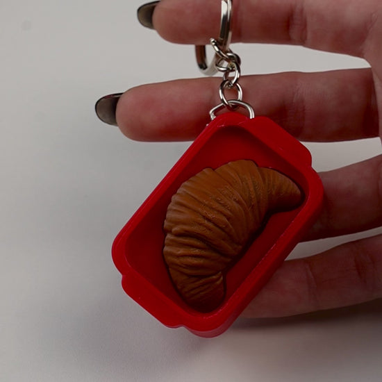 llavero antiestrés beetle print croissant en uso presionando boton clicker
